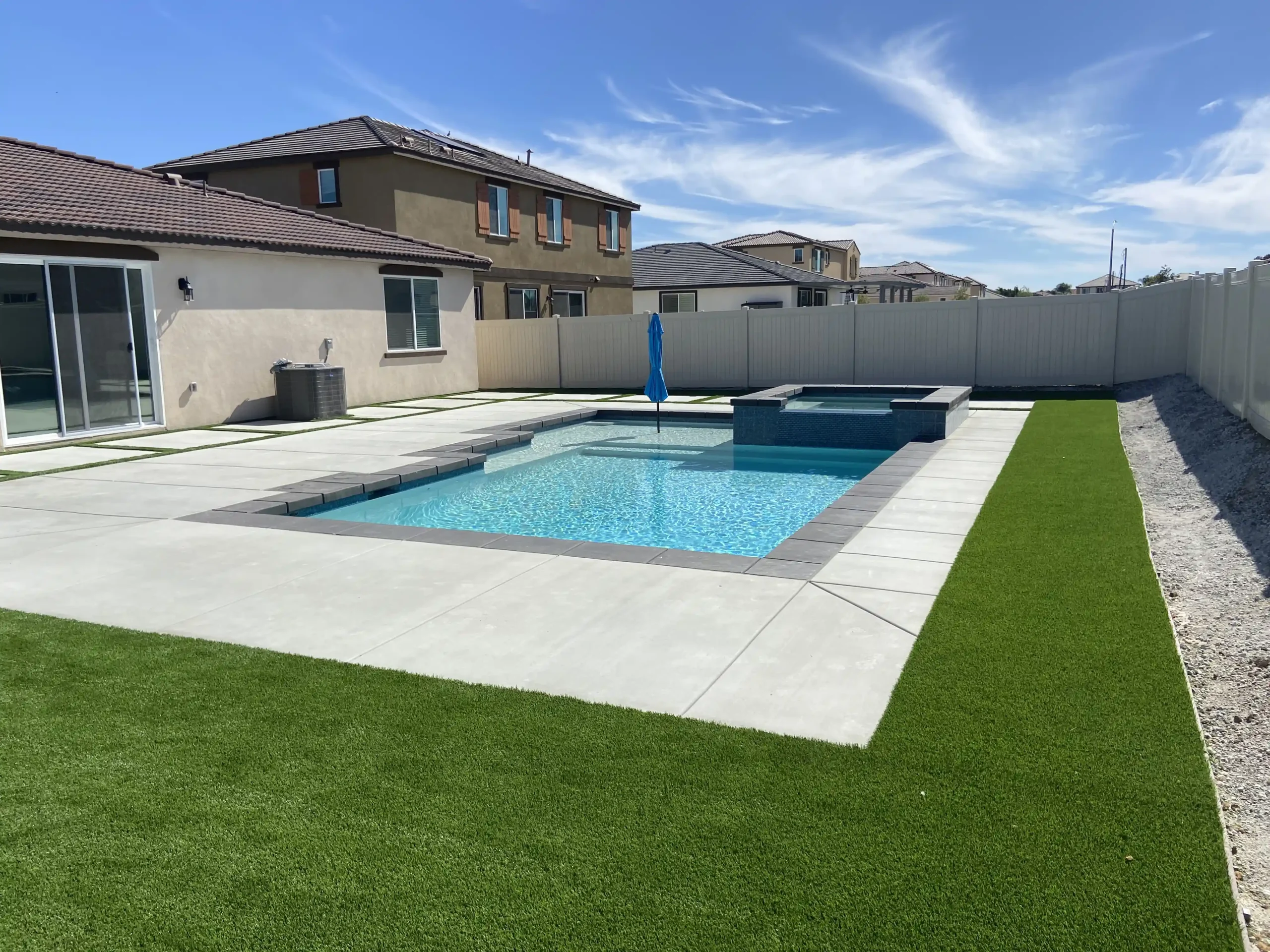 The finished project of a swimming pool with all the pool and spa installed including the pool tiles, and grass.