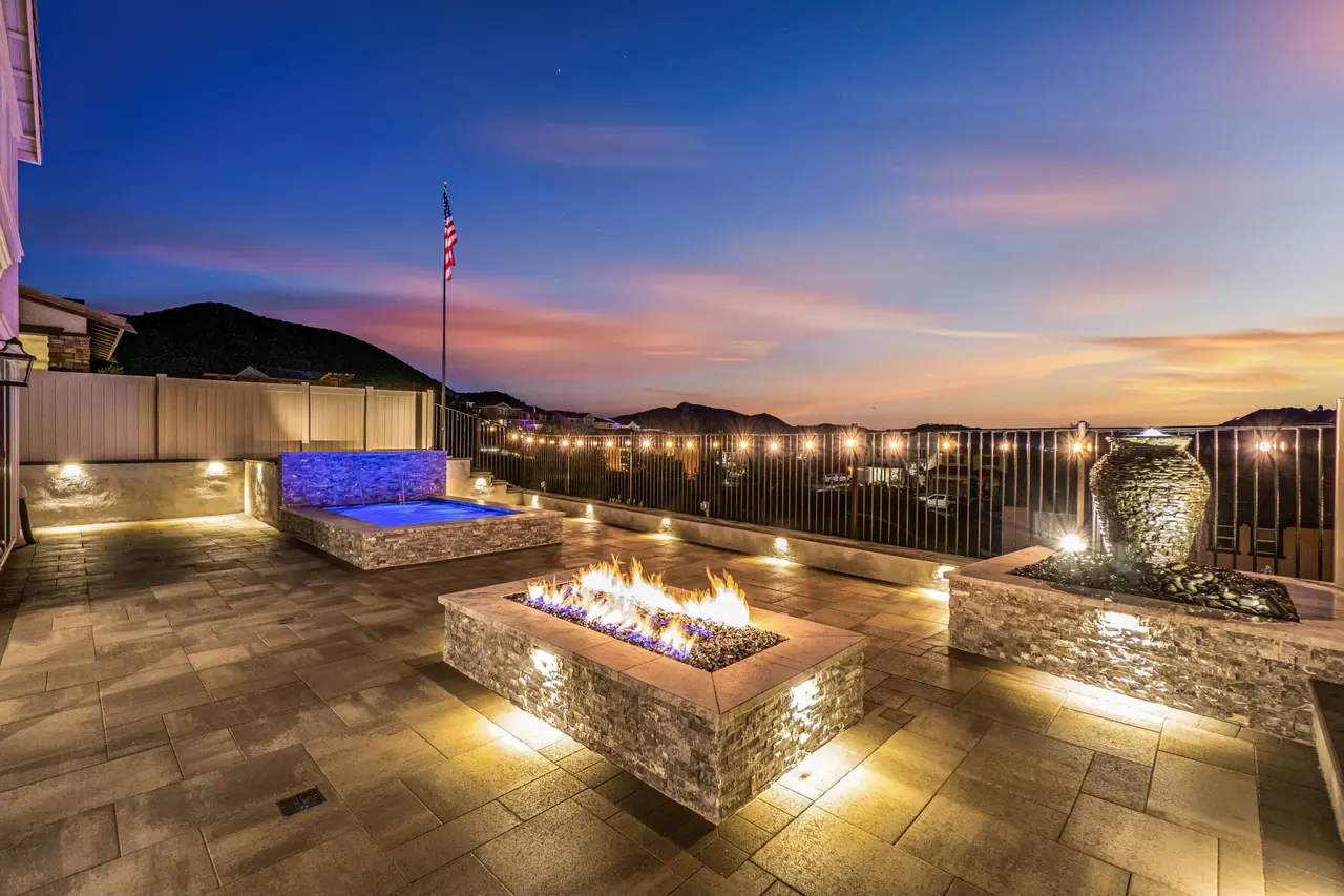 the finished outcome of pool construction by California Custom Pools with a firepit, lightings, and large jar decoration