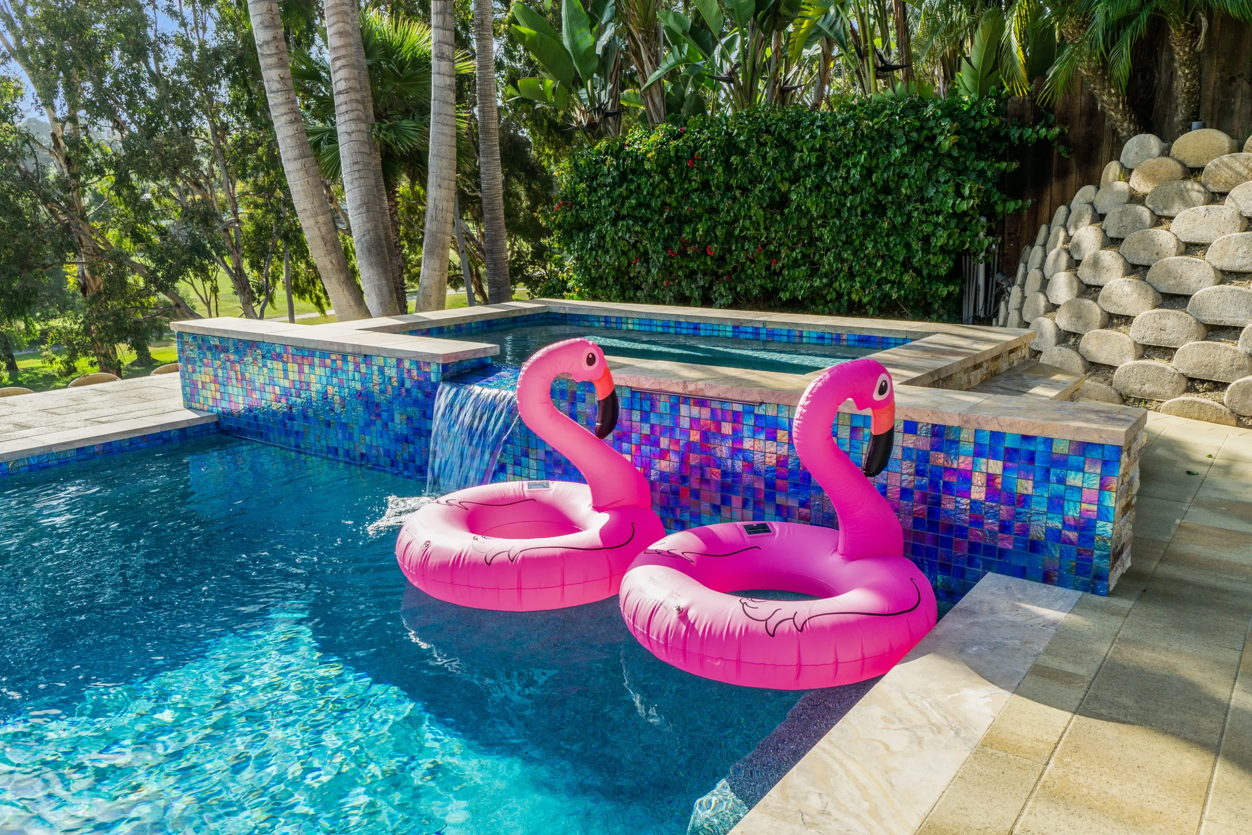 Swimming pool with pink flamingo floats and vibrant tile design in Oceanside, California