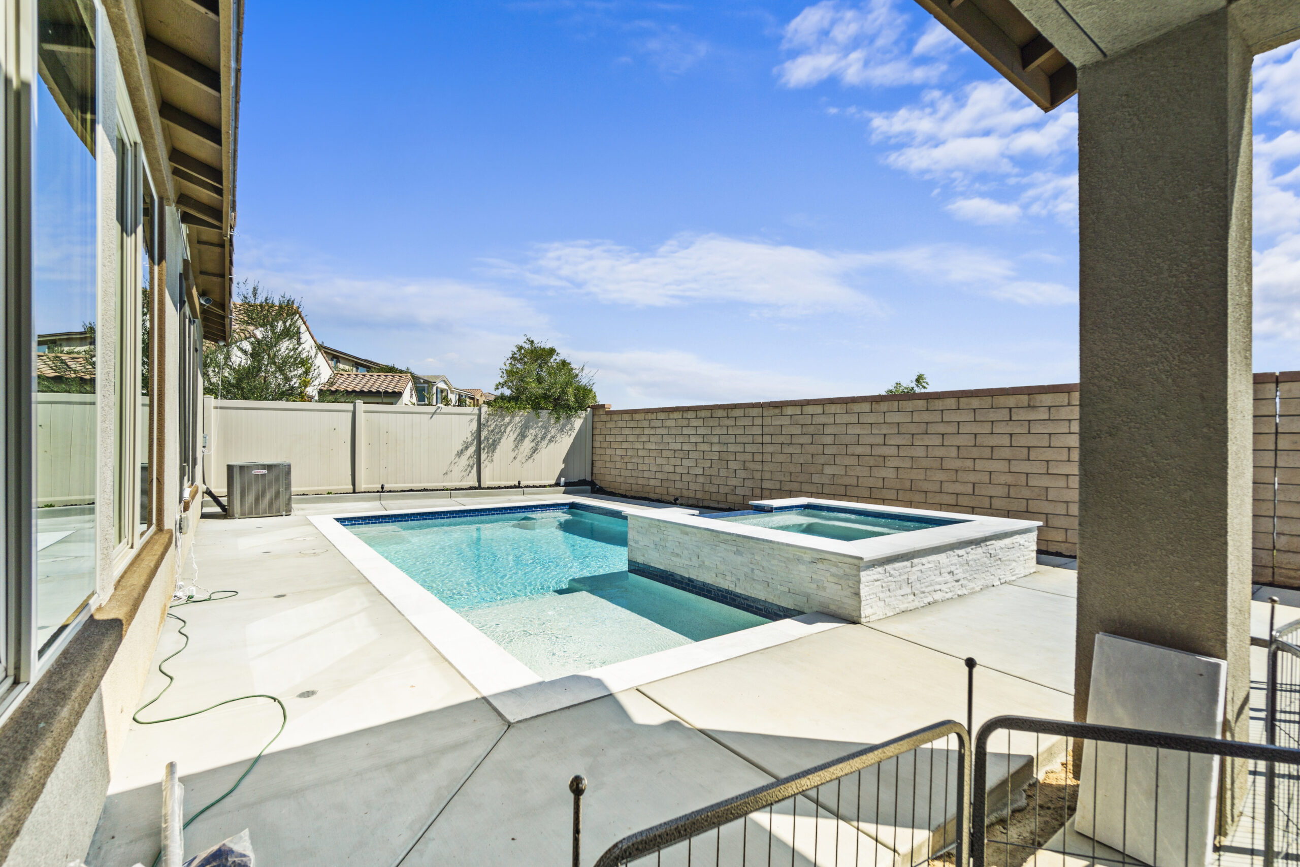 Contemporary backyard pool with spa and privacy wall