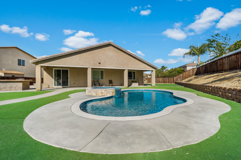 Elegant pool with cascading waterfall and spacious backyard.