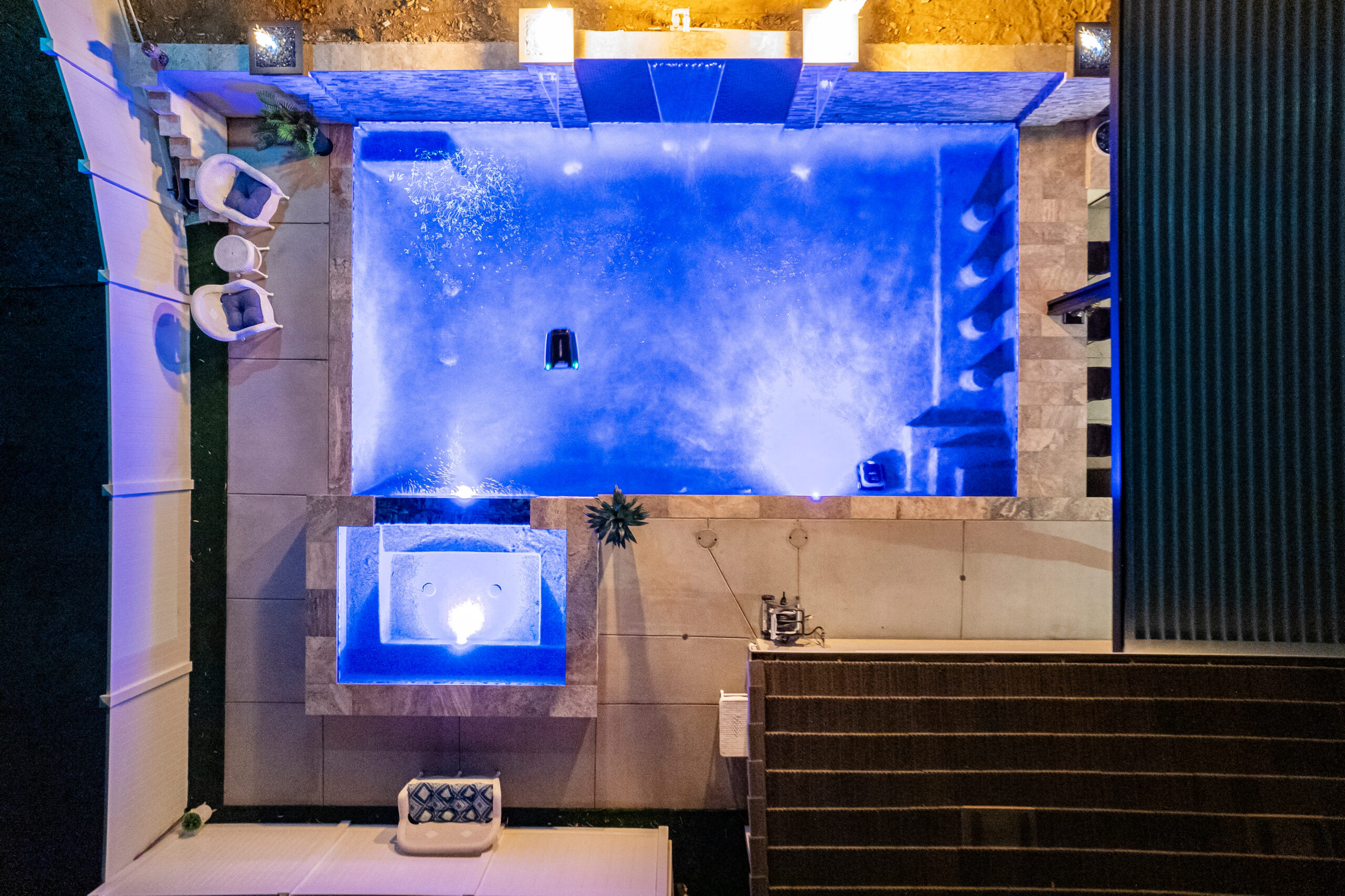 Stunning aerial view of a pool with ambient night lighting and water features.