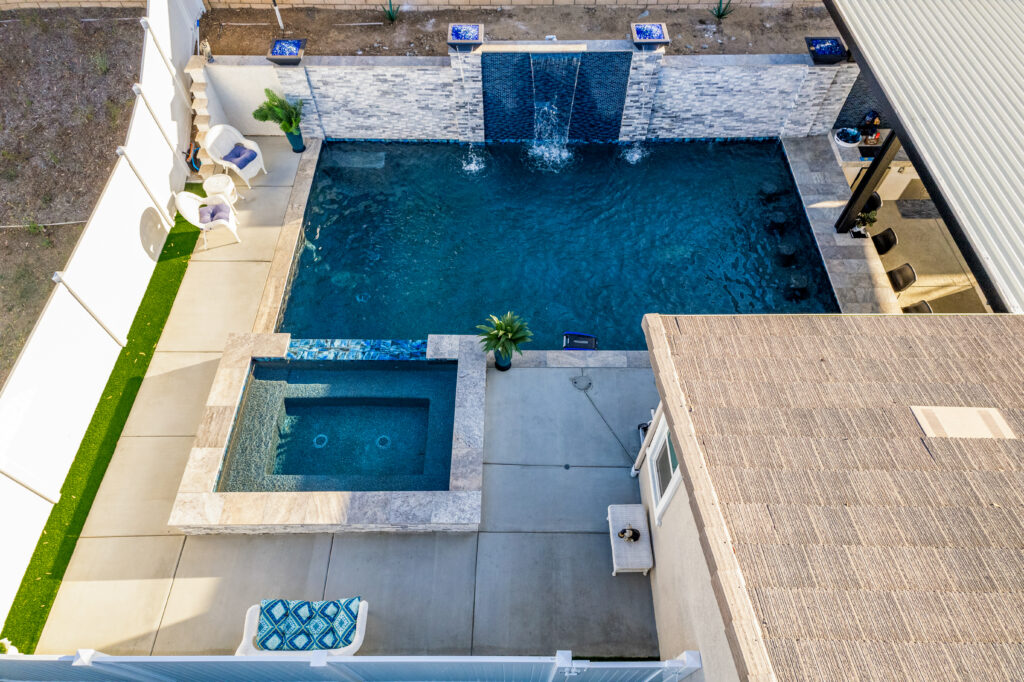 Elegant pool with cascading water feature and cozy seating.