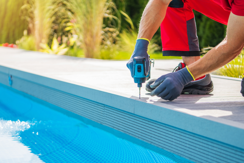 Worker installing decking around a custom pool in California.