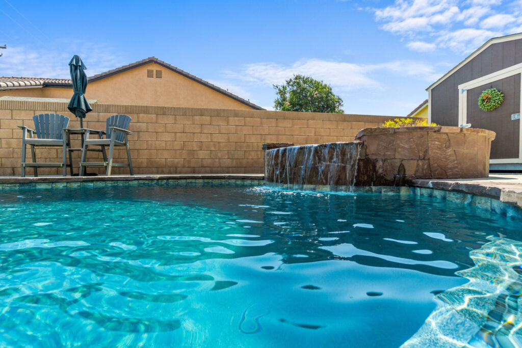 California custom pool with waterfall feature and patio seating.